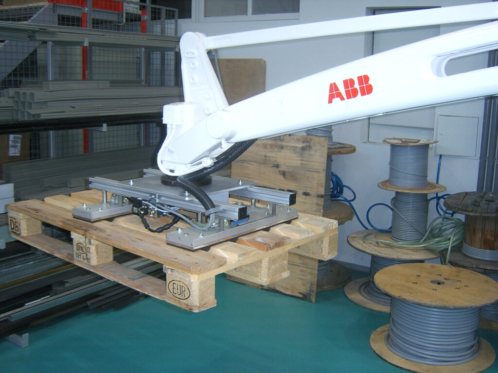 ein Flächengreifer, der an einem Roboterarm befestigt ist, hebt eine Europalette an
